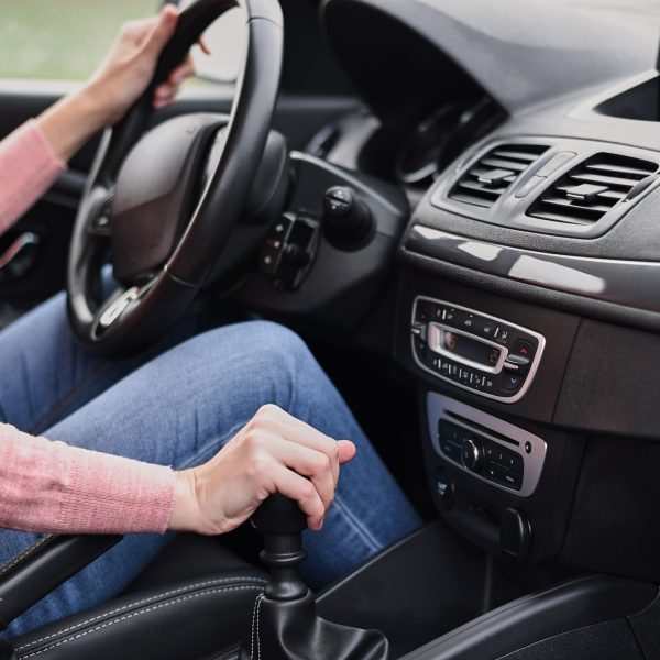 Woman driving car. Female hand change speed on the manual gearbox